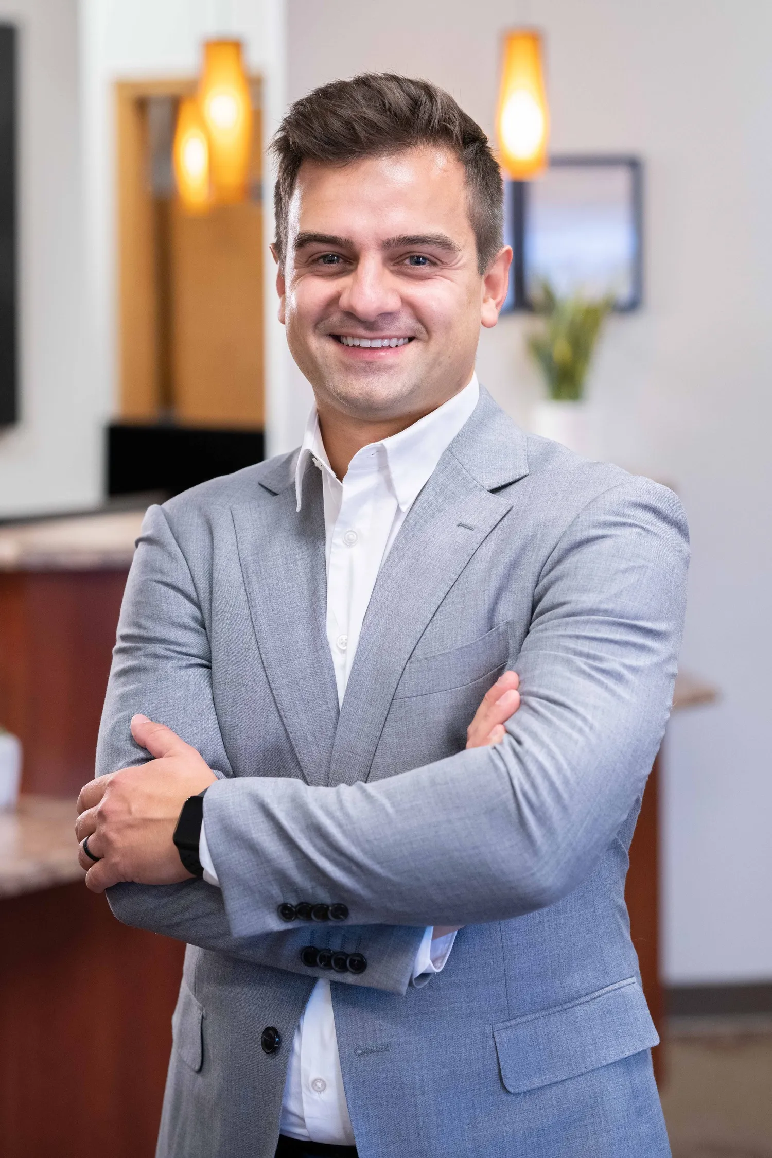 Smiling dentist in a grey suit with his arms crossed inside the Ham Lake Dental office